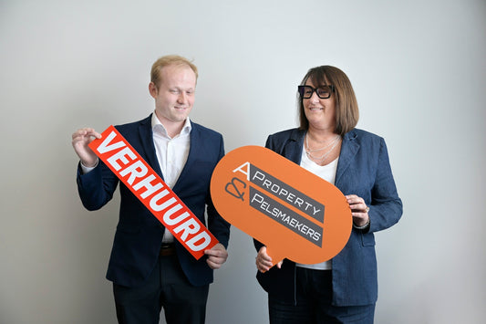Two real estate agents holding rented and company signs.